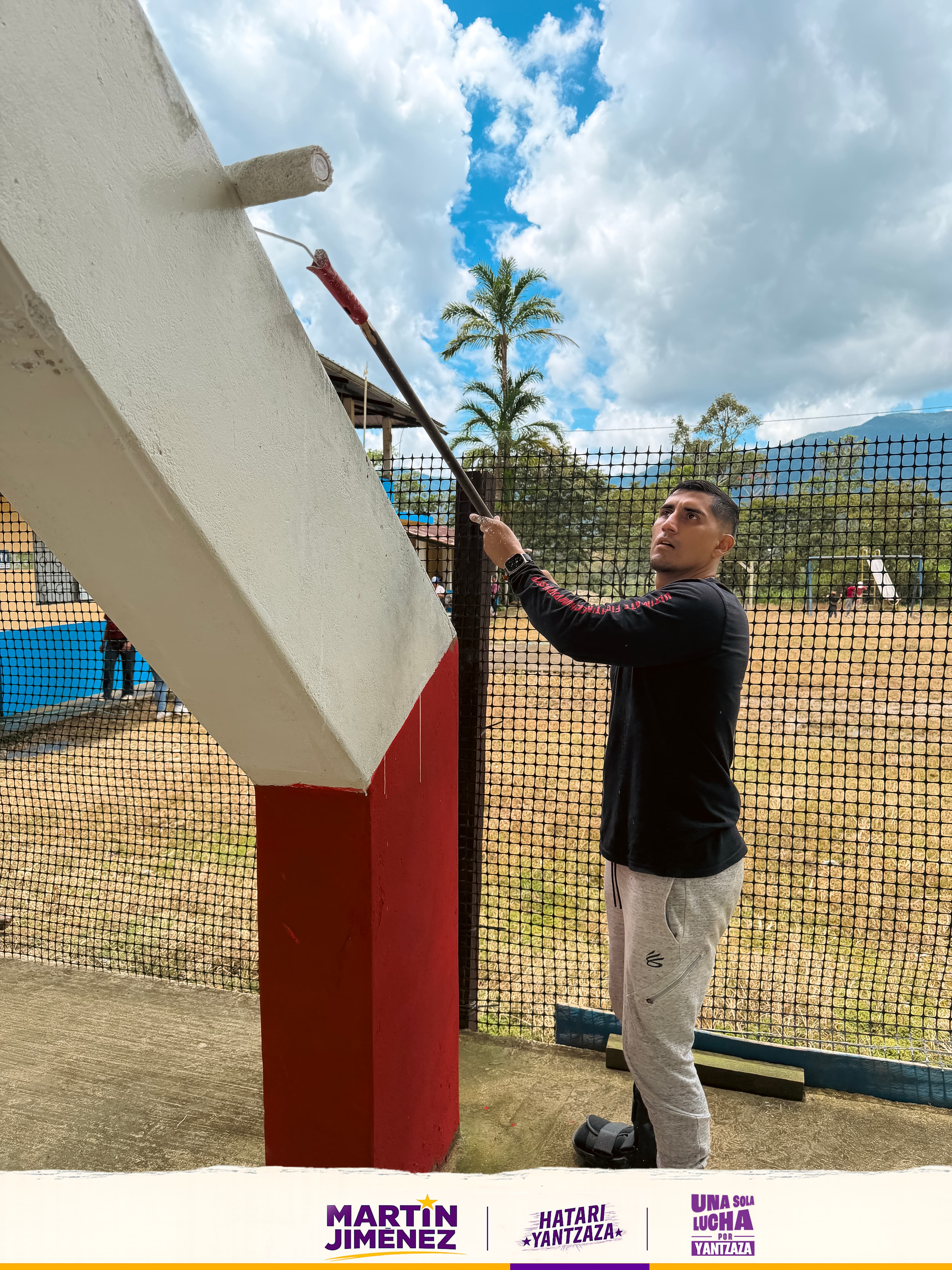 Joven voluntario pintando infraestructura deportiva comunitaria